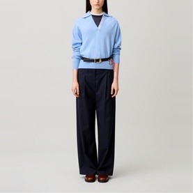 Model wearing Claude Pierlot Logo Polo Sweater in sky blue with navy wide-leg trousers and brown loafers.