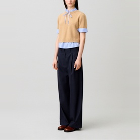 Model wearing Claude Pierlot Stripe Hybrid Sweater in clear, with striped poplin collar and bow tie, styled with wide-leg navy trousers.