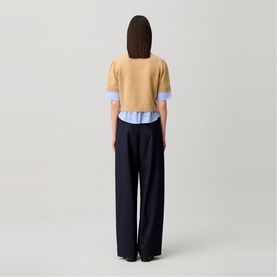 Model wearing Claude Pierlot Stripe Hybrid Sweater in Clear with navy wide-leg trousers, rear view showing striped poplin hem detail.