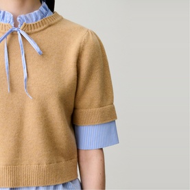 Model wearing Claude Pierlot Stripe Hybrid Sweater in camel with blue striped poplin Victorian collar and bow tie detail, short sleeves