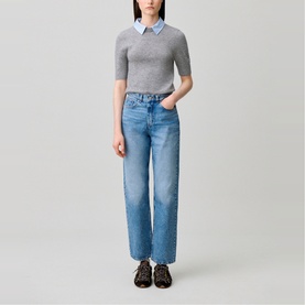 Model wearing Claude Pierlot Collar Knit Sweater in black with removable striped collar, styled with light blue wide-leg jeans and black sandals.