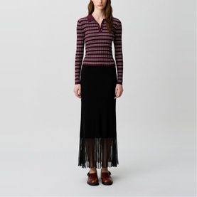 Model wearing Claude Pierlot Rib Knit Skirt in black, maxi length with sheer fringed hem, styled with a striped ribbed polo top and dark loafers