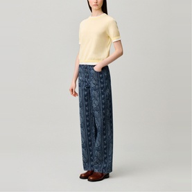 Model wearing Claude Pierlot Contrast Knit T-Shirt in Clear with scalloped trim, styled with blue printed wide-leg trousers and brown loafers.