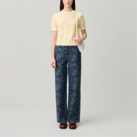 Model wearing Claude Pierlot Contrast Knit T-Shirt in Clear with scalloped trim, styled with navy printed wide-leg trousers and brown loafers.