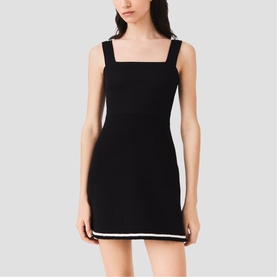 Model wearing black sleeveless mini dress with white contrast trim at hem and square neckline with embellished straps