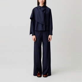 Model wearing Claude Pierlot Shawl Draped Jacket in blue with draped panel, styled with matching wide-leg trousers and brown loafers.