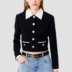 Model wearing Maje red cropped jacket with white collar, gold buttons, and contrast trim, styled with blue jeans and belt
