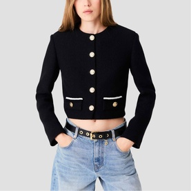 Model wearing Maje red cropped jacket with gold buttons and contrast trim, styled with light blue jeans and black belt