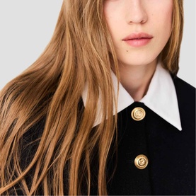 Model wearing Maje Womens French Dress in red, featuring white collar and gold disc buttons, close-up detail shot