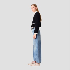 Model wearing Maje Womens French Dress in red, styled with light blue wide-leg jeans and nude trainers, side profile view.