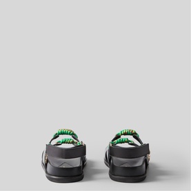 Black leather sandals rear view, green ruched strap detail across heel, silver-tone buckle fastening, flat sole