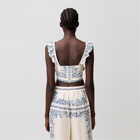 Model wearing ivory and blue floral print ruffle-strap crop top, styled with matching wide-leg trousers, back view