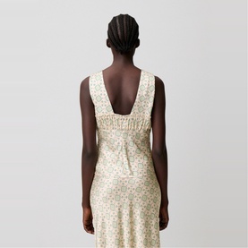 Model wearing cream floral sleeveless midi dress with ruched back detail and low scoop back, rear view