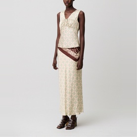 Model wearing cream patterned sleeveless maxi dress with ruched neckline, styled with a printed scarf and brown strappy sandals.