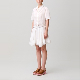 Model wearing white short-sleeve cropped shirt and white broderie skirt, styled with brown platform mules