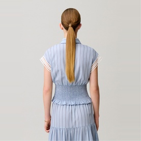Model wearing Claude Pierlot black sleeveless dress with smocked waist, pintuck detail, tiered hem and lace trim, seen from behind