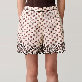 Model wearing Claude Pierlot light print floral shorts with scalloped lace hem border, styled with a brown top.