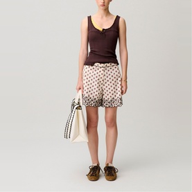 Model wearing Claude Pierlot light print polka dot shorts with dark brown tank top, styled with a tote bag and lace-up shoes.