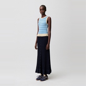 Model wearing Claude Pierlot black pleated maxi skirt with blue striped knit tank top and blue trainers