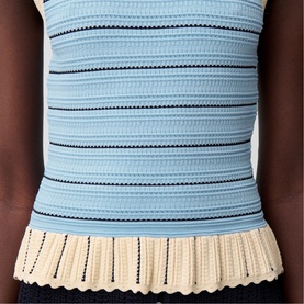 Model wearing Claude Pierlot black striped knit top with crochet frill hem detail, styled with dark trousers