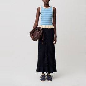 Model wearing Claude Pierlot black ribbed maxi skirt with blue striped knit top, styled with brown bag and navy sandals