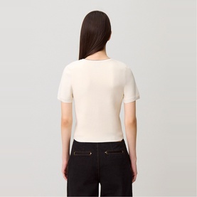 Model wearing cream short-sleeve ribbed knit top, styled with black trousers, rear view
