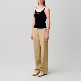 Model wearing Claude Pierlot black ribbed tank top with white trim, styled with beige wide-leg trousers and cream shoes