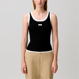Model wearing Claude Pierlot black ribbed tank top with white contrast trim and scoop neck, styled with beige trousers.