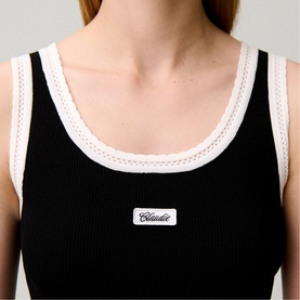 Model wearing Claude Pierlot black ribbed vest top with white contrast trim and logo badge detail, close-up crop view