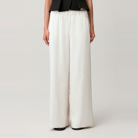 Model wearing Claude Pierlot wide-leg trousers in clear white with elasticated waist, styled with a black top.