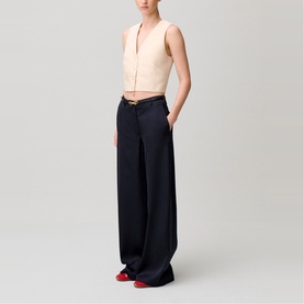 Model wearing wide-leg navy trousers with cream sleeveless top and red shoes, side view showing relaxed silhouette