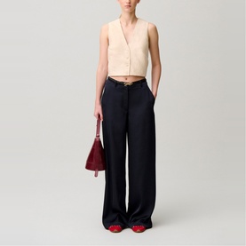 Model wearing wide-leg navy trousers and cream sleeveless top, carrying a small burgundy handbag, styled with red heeled shoes.