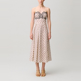 Model wearing cream polka dot midi dress with sweetheart neckline, lace trim, and spaghetti straps, styled with gold strappy heels