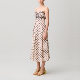 Model wearing strapless cream polka dot midi dress with ruffle bust detail, styled with gold block-heel sandals