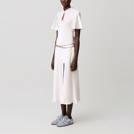 Model wearing Claude Pierlot Womens French Dress in clear white, with flutter sleeves, keyhole neckline, front slit and gold chain belt.