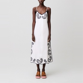 Model wearing white midi slip dress with black paisley embroidery at bust and hem, styled with pink strappy heels