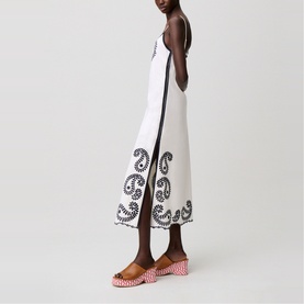 Model wearing white sleeveless midi dress with black swirl embroidery hem detail, styled with pink woven block-heel mules
