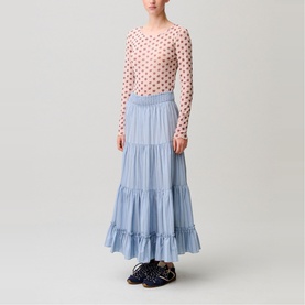 Model wearing a light blue tiered maxi skirt with ruffled hem, styled with a pink polka dot long-sleeve top and dark sandals