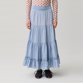 Model wearing a light blue tiered maxi skirt with elasticated waist, styled with a pink floral top and dark lace-up shoes.