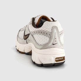 Nike men's trainer in Phantom Tan Sail Baroque, rear three-quarter view, white mesh upper, brown Swoosh, gum rubber sole.