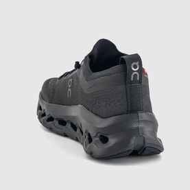 On Running Cloudmonster trainer in black, rear three-quarter view showing chunky CloudTec sole and mesh upper.