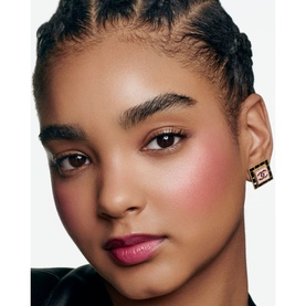 Model wearing Chanel Multi-Use Duo Stick in Pure Glow, showing warm blush on cheeks and berry-toned lip colour, with gold Chanel earring.