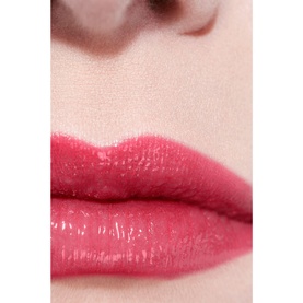 Close-up of lips wearing Chanel Hydrating Beautifying Tinted Lip Balm in Electric Vibe, a glossy bright pink-red shade