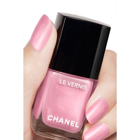 Chanel Le Vernis Longwear Nail Colour in Party Girl, sheer pink shimmer varnish, held between finger and thumb showing painted nails