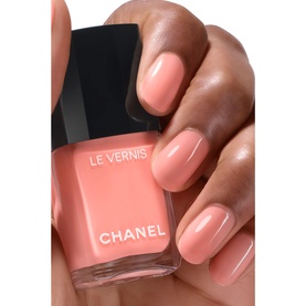 Chanel Le Vernis Longwear Nail Colour in Party Girl, a warm coral-peach shade, shown on hand with bottle