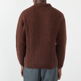 Model wearing Edwin Crew Neck jumper in Rum Raisin, chunky boucl&eacute; knit, back view, styled with grey trousers.