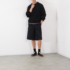 Model wearing Edwin Black Crew Neck knit with black cargo shorts, black socks and canvas trainers