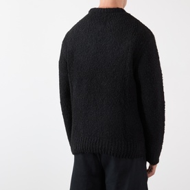 Model wearing Edwin black boucle crew neck knit sweater, back view, paired with black trousers
