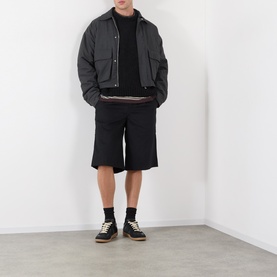 Model wearing Edwin Black Crew Neck knit, styled with dark shorts, cropped jacket and black socks with contrast trainers.