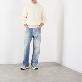 Model wearing Edwin Crew Neck in off white wool blend, styled with light wash distressed jeans and grey trainers.